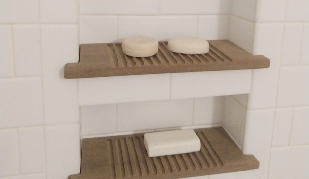 bar shampoo, conditioner, and body soap sitting on homemade wooden soap holders